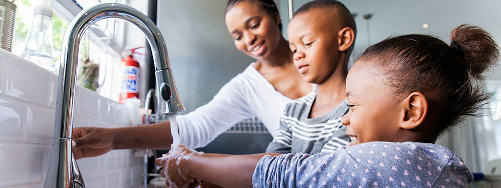 family-washing-hands-lg Family washing their hands together at the kitchen sink.